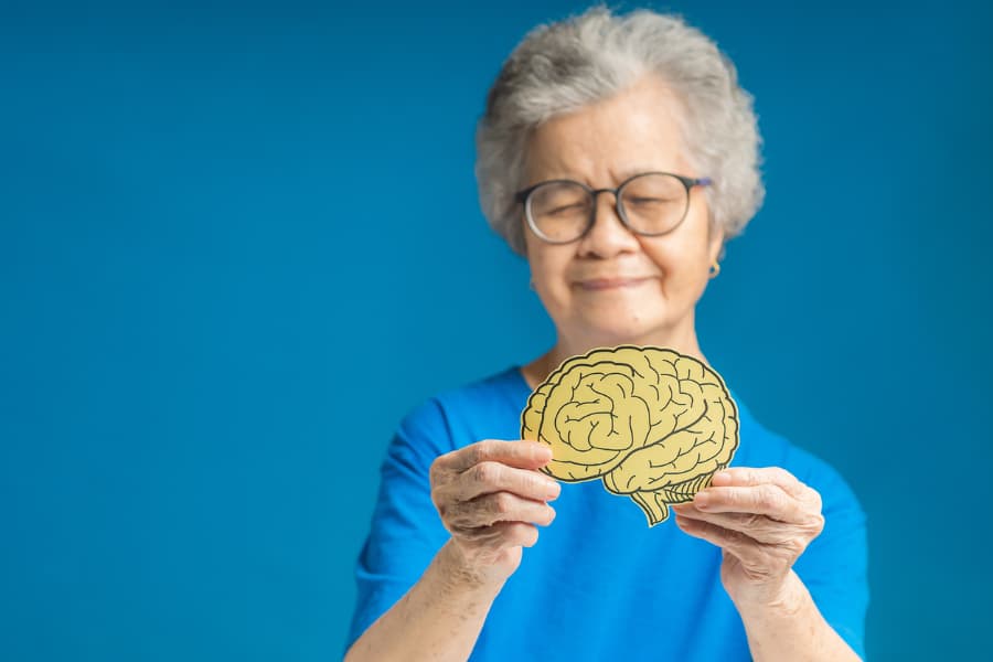 Elderly individual holding paper brain cutout