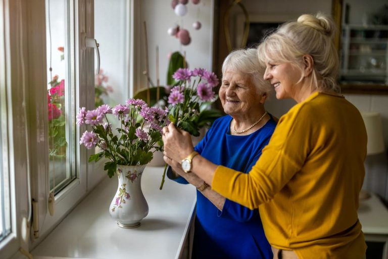 Elderly resident decorating living quarters of memory care community with family member
