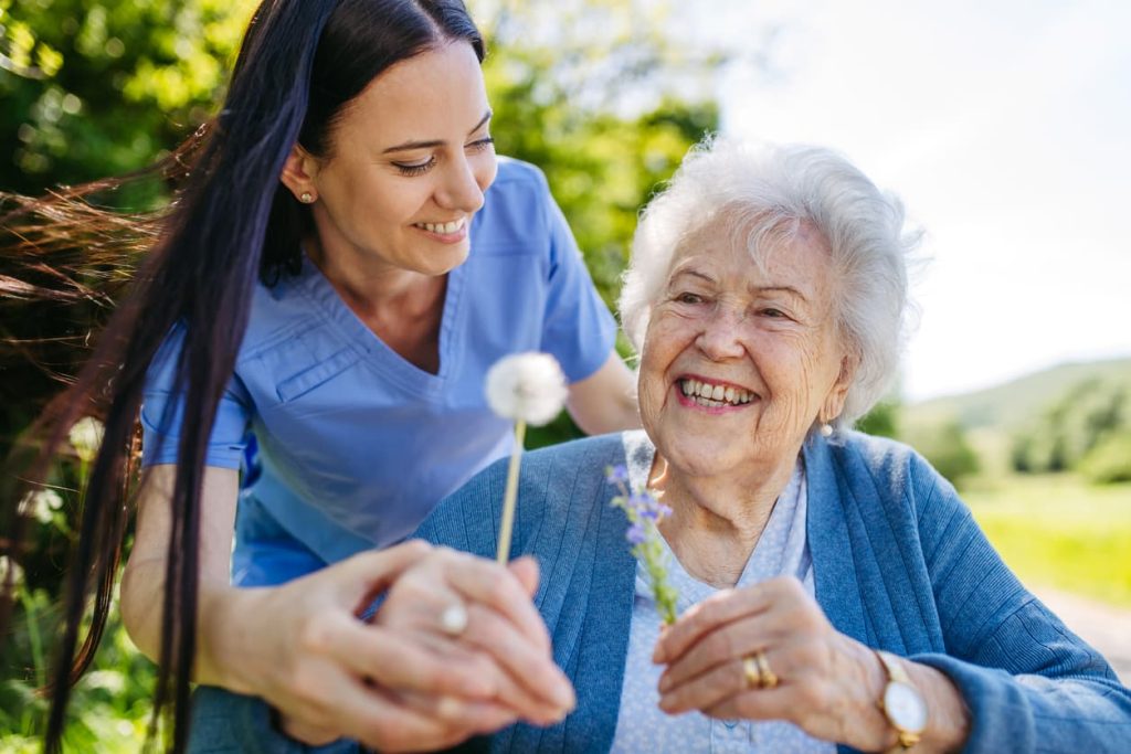 Caregiver holding dandelion talking to senior in wheelchair