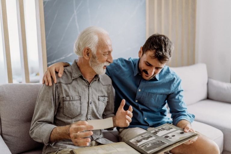 Memory care resident sitting on couch with family member looking at family photos
