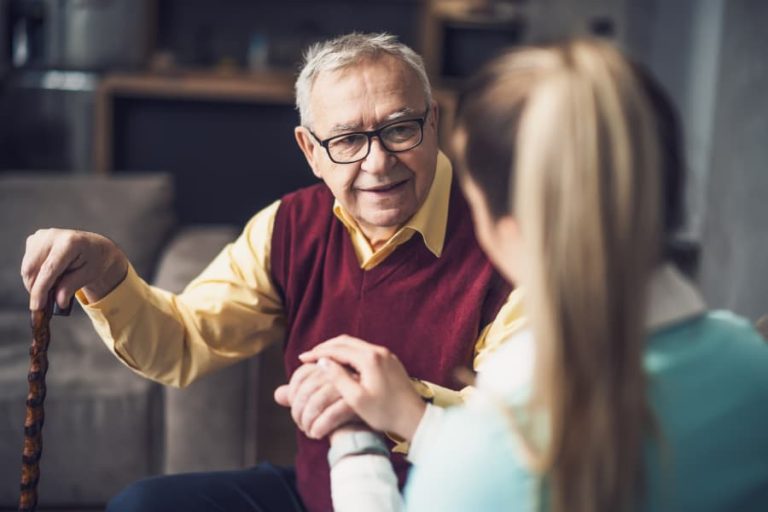 Caregiver and senior resident holding hands