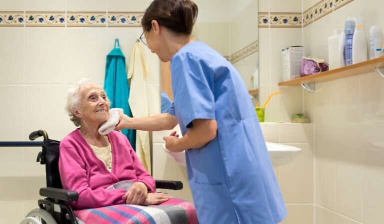Caregiver helping resident in bathroom while sitting in wheelchair