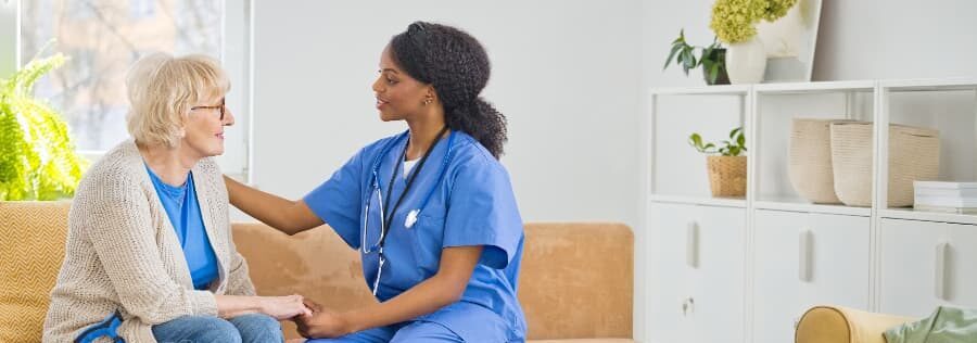 Home caregiver taking care of resident and holding their hands