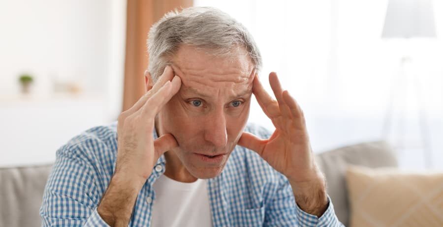 Senior person sitting with hands on head
