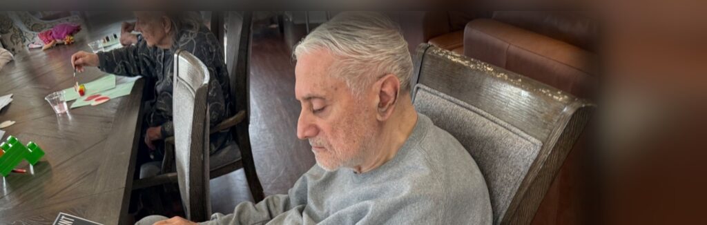 A Fox Trail memory care resident looking through a large print book during a group activity