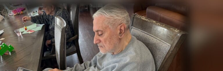 A Fox Trail memory care resident looking through a large print book during a group activity
