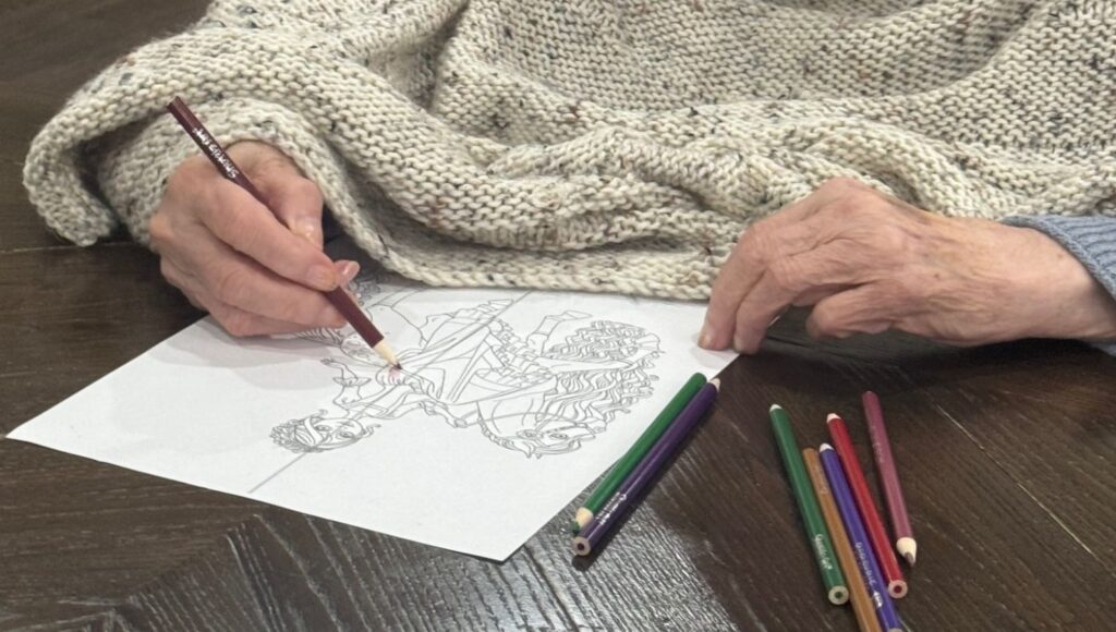 Close-up of a Fox Trail resident colouring a detailed page with coloured pencils during a SPARK session