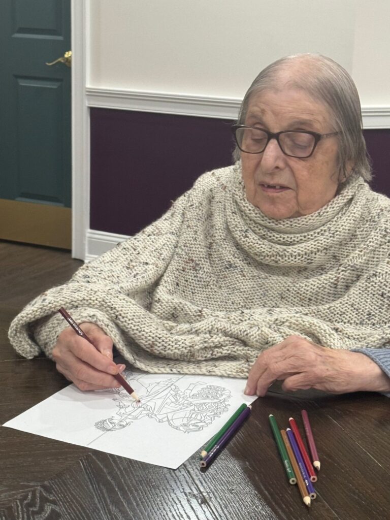 A Fox Trail resident wearing a knitted shawl colouring at a table during a SPARK creative-expression session