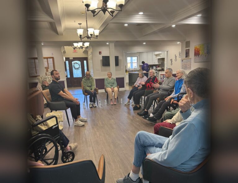 Residents and a team member seated together for a group activity in the common room of a Fox Trail memory care home in New Jersey
